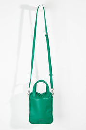 A model wearing size OneSize of the Leap Vegan Crossbody Bag in colour Peacock (Green), from the front, showing the whole outfit