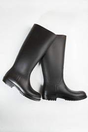 A model wearing size 36 of the Otoki Waterboot Calf Rainboot in colour Black (Black), from the front, showing the whole outfit