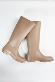 A model wearing size 36 of the Otoki Waterboot Calf Rainboot in colour Soy, from the front, showing the whole outfit