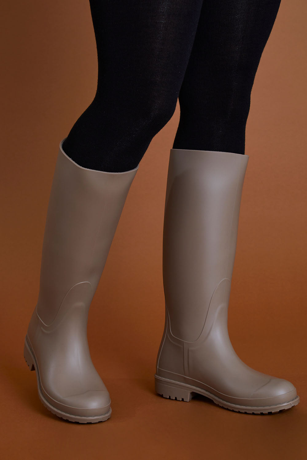 A model wearing size 40 of the Otoki Waterboot Calf Rainboot in colour Soy, from the front, cropped image