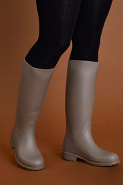 A model wearing size 40 of the Otoki Waterboot Calf Rainboot in colour Soy, from the front, cropped image