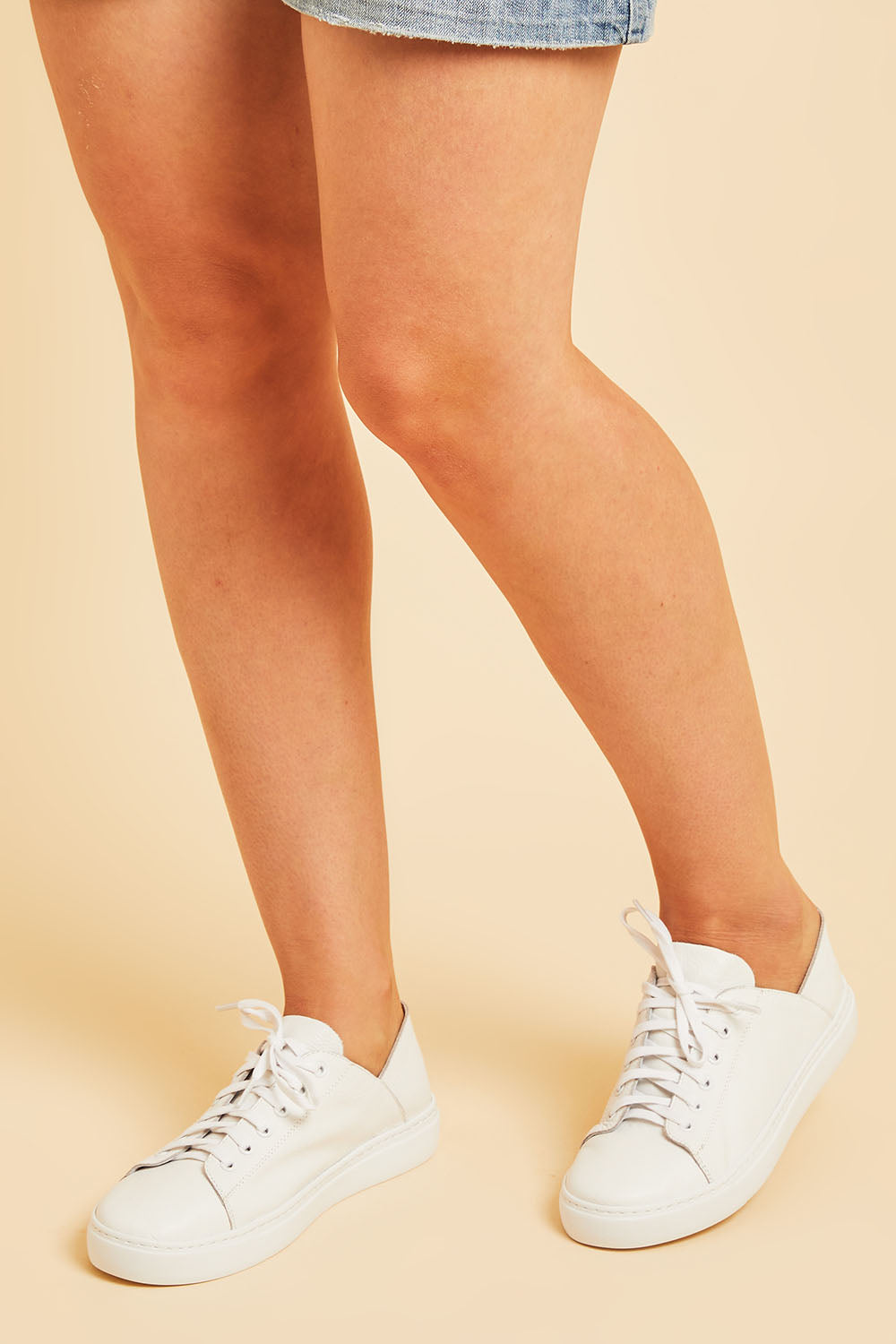 A model wearing size 37 of the Oskher Leather Sneaker in colour White (White), from the front, cropped image