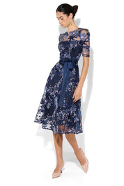 A model wearing the Loren Lace Midi Dress in colour Navypink (Blue), from the front, showing the whole outfit