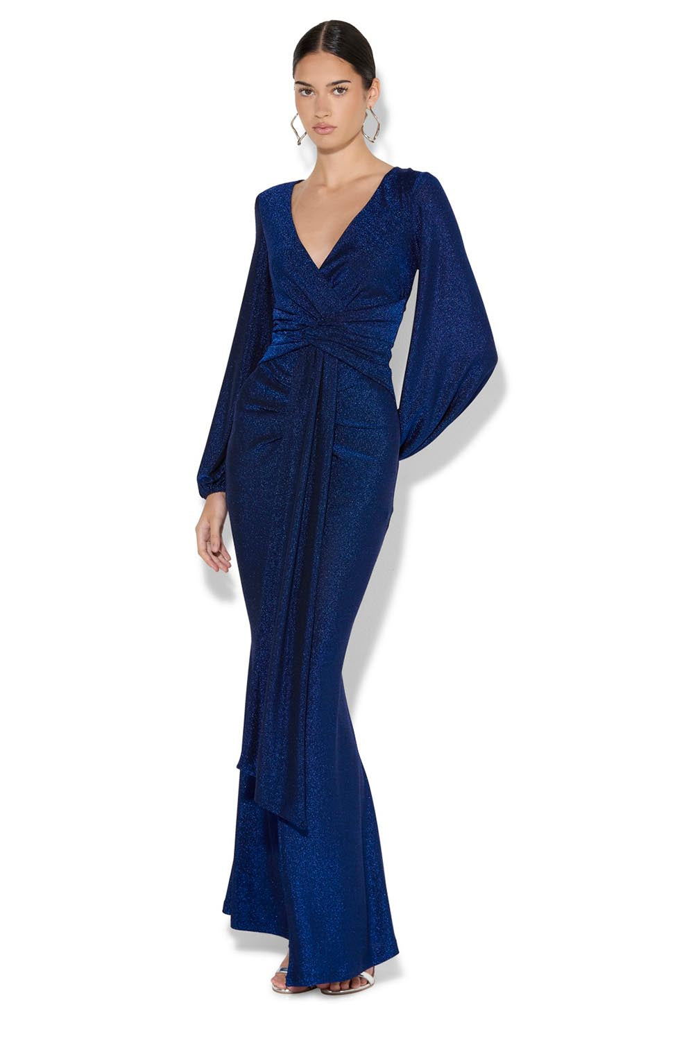A model wearing the Serena Shimmer Maxi Gown in colour Sapphire (Blue), from the front, showing the whole outfit