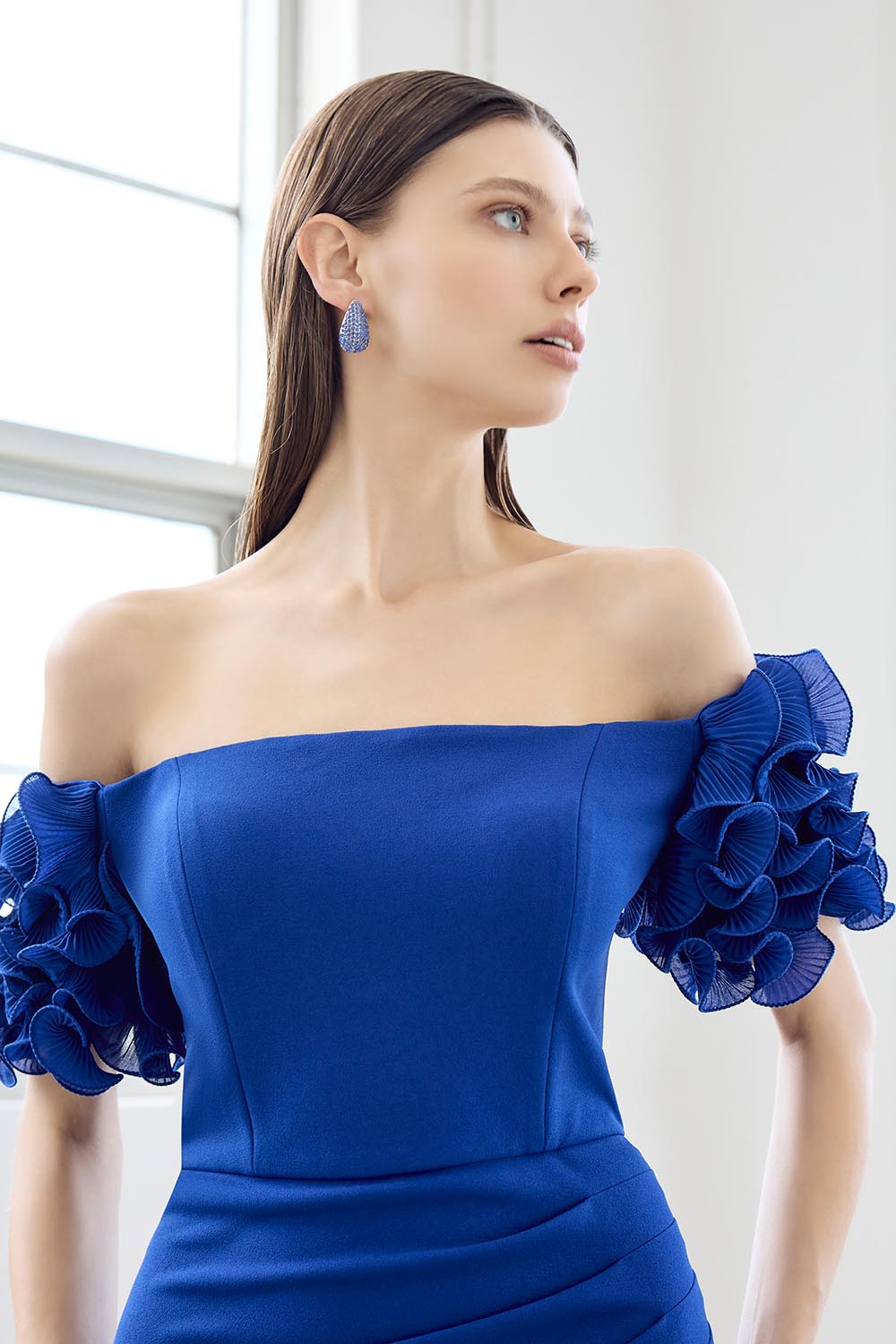 A model wearing the Diana Ruffle Sleeve Gown in colour Sapphire (Blue), from the front, cropped image