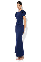 A model wearing the Monet Rosette Sleeve Gown in colour Navy (Blue), from the front, showing the whole outfit