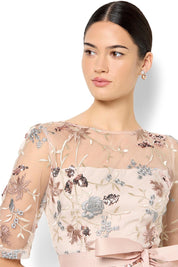 A model wearing the Pippa Embroidered Dress in colour Mink (Pink), from the front, cropped image