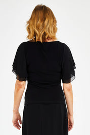 Model Naomi wearing size 10 of the Brenda Top in colour Black (Black), from the back