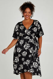 Model Alexis wearing size 16 of the Alanah Wrap Dress in colour Tulips (Black), from the front, cropped image