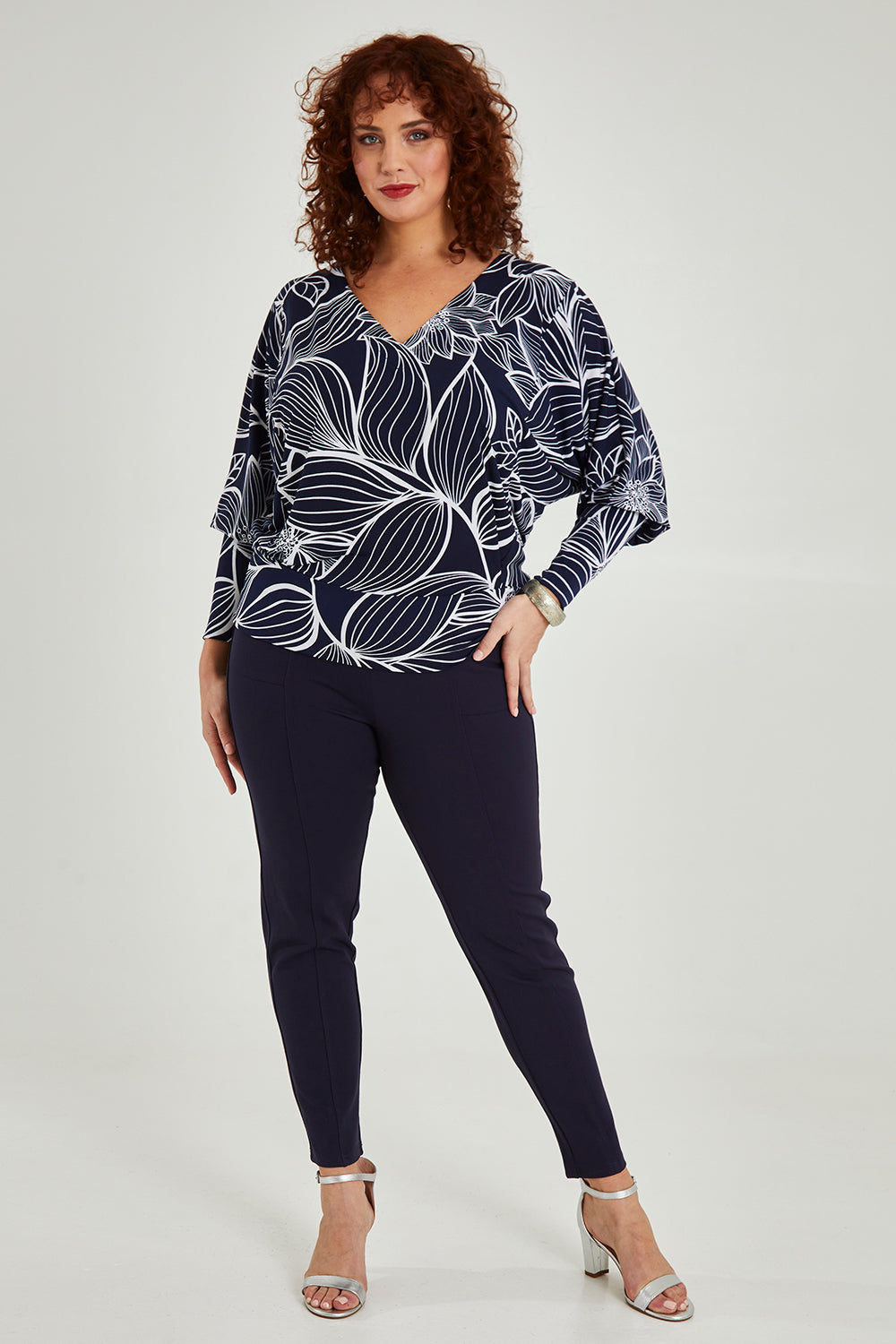 Model Maddy wearing size 16 of The Printed Kelly Blouse in colour Navyleaves (Blue), from the front, showing the whole outfit