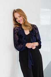 Model Katie wearing size 10 of the Penny Shrug in colour Navyfleur (Blue), from the front, showing the whole outfit
