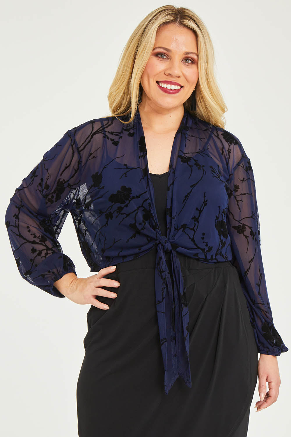 Model Katie wearing size 16 of the Penny Shrug in colour Navyfleur (Blue), from the front, cropped image