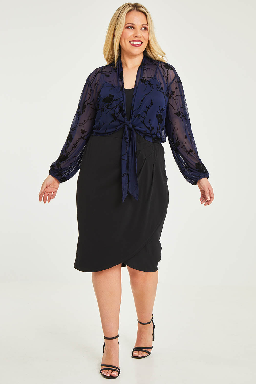 Model Katie wearing size 16 of the Penny Shrug in colour Navyfleur (Blue), from the front, showing the whole outfit