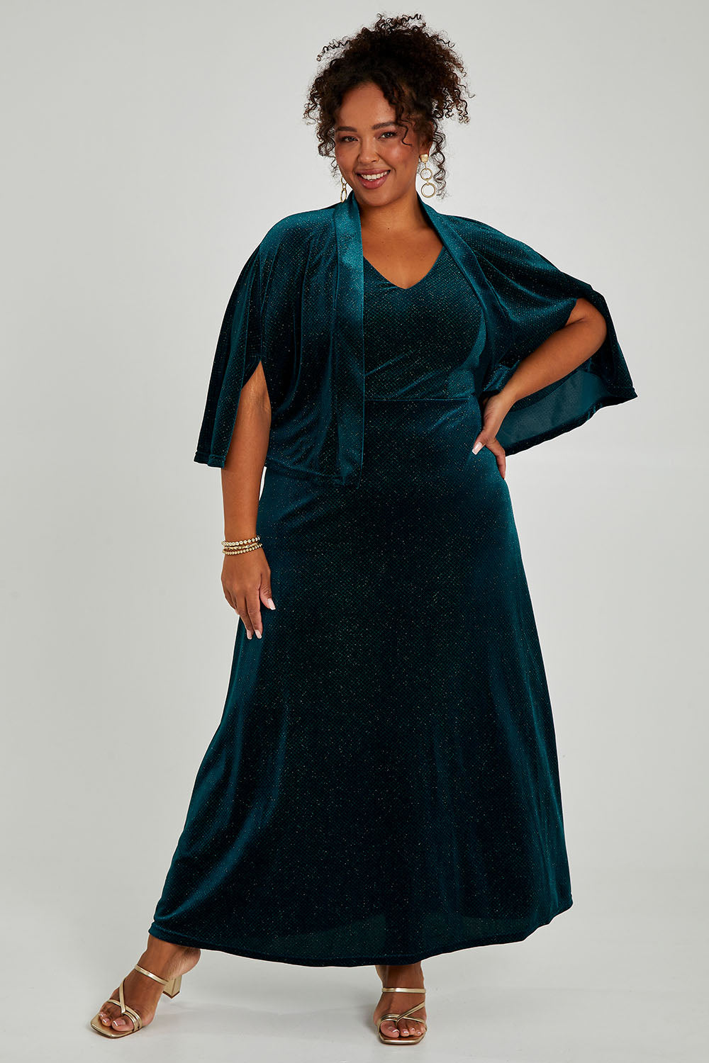 Model Alexis wearing size 16 of the Lynette Velvet Cape in colour Jade (Green), from the front, showing the whole outfit
