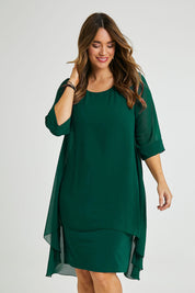 Model Laura wearing size 14 of the Bethany Dress in colour Pine (Green), from the front, cropped image
