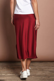 Model Madeline wearing size 10 of the Loulou Satin Skirt in colour Shiraz (Red), from the back