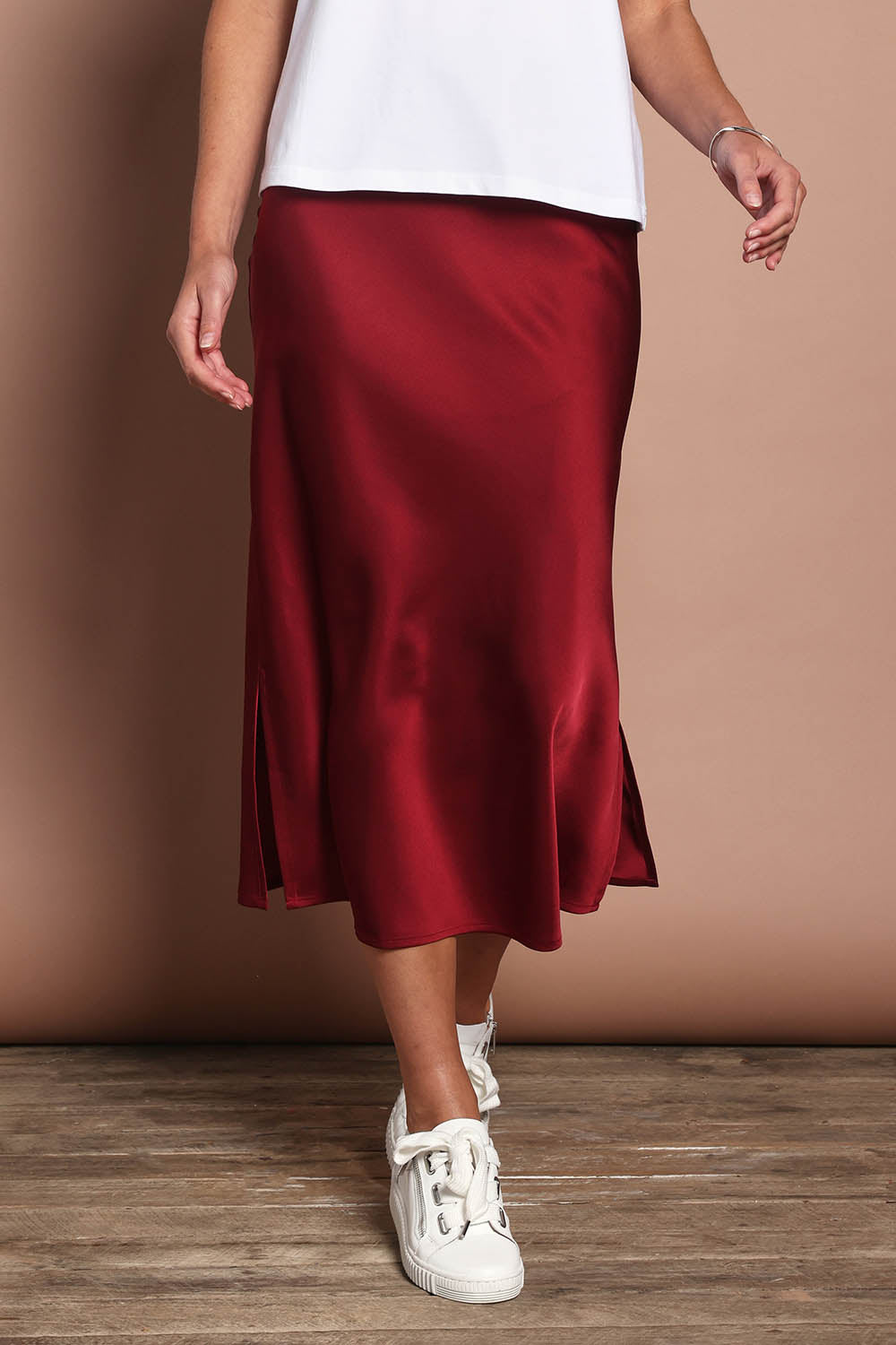 Model Madeline wearing size 10 of the Loulou Satin Skirt in colour Shiraz (Red), from the front, cropped image