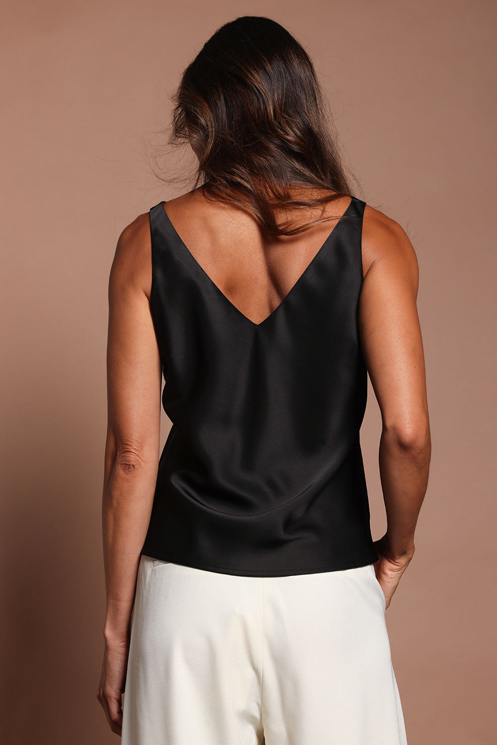 Model Madeline wearing size 10 of the Loulou Satin Camisole in colour Black (Black), from the back