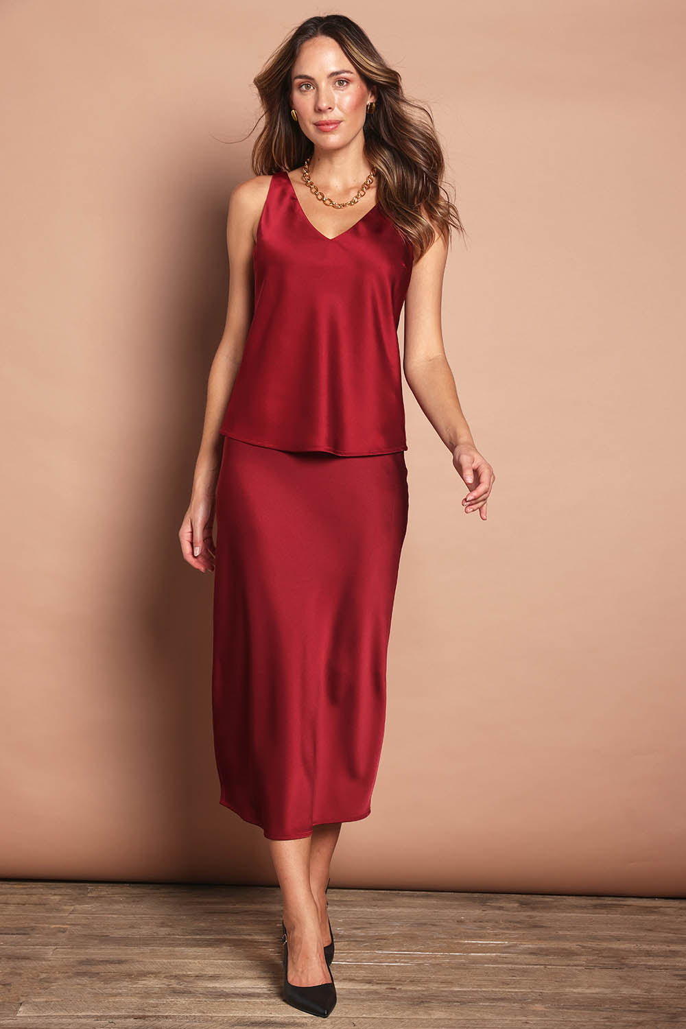 Model Madeline wearing size 10 of the Loulou Satin Camisole in colour Shiraz (Red), from the front, showing the whole outfit