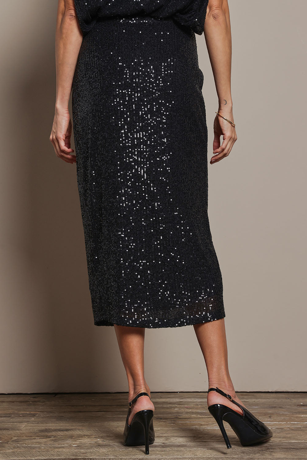 Model Amanda wearing size 10 of the Reegan Sequin Skirt in colour Black (Metallics), from the back