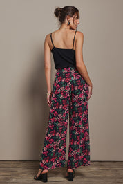 Model Madeline wearing size 10 of the Annette Pants in colour Blossom (Black), from the back