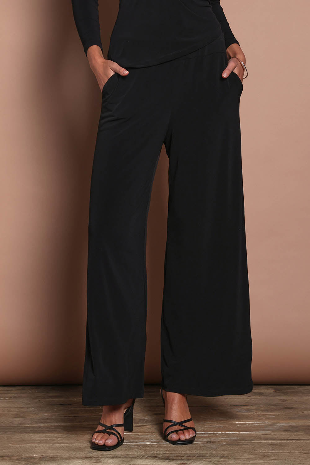 Model Madeline wearing size 10 of the Kristi Pants in colour Black (Black), from the front, cropped image