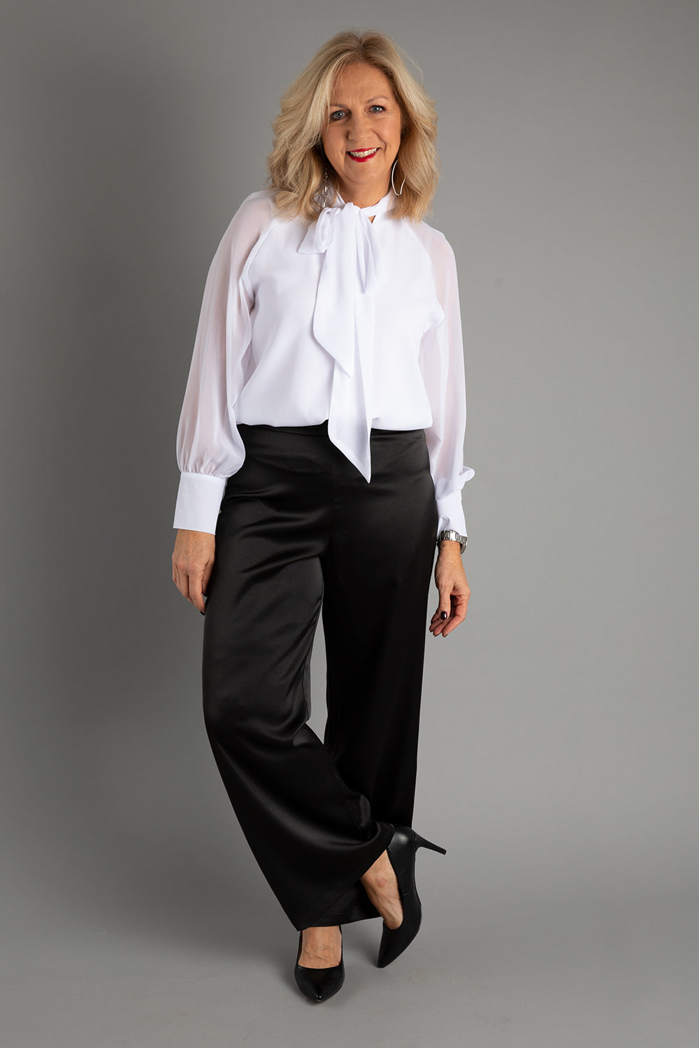 Model Sandy wearing size 10 of the Tina Pants in colour Black (Black), from the front, showing the whole outfit