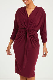Model Noli wearing size 14 of the Nancy Dress in colour Port (Red), from the front, cropped image