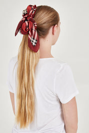 A model wearing the Merin Hair Scarf in colour Redcheck (Red), from the back