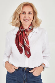 Model Sandy wearing size OneSize of the Merin Hair Scarf in colour Redcheck (Red), from the front, cropped image