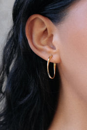 A model wearing the Cinta Hoop Earrings in colour Gold (Metallics), from the front, showing the whole outfit