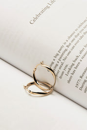 A model wearing the Cinta Hoop Earrings in colour Gold (Metallics), from the front, showing the whole outfit