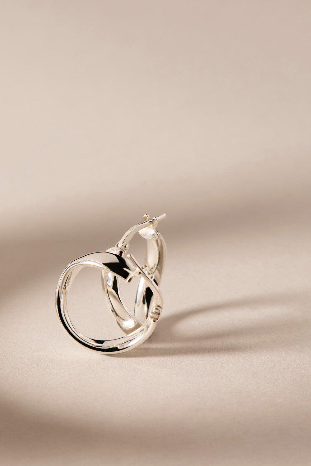 A model wearing the Eddy Hoop Earrings in colour Silver (Metallics), from the front, showing the whole outfit