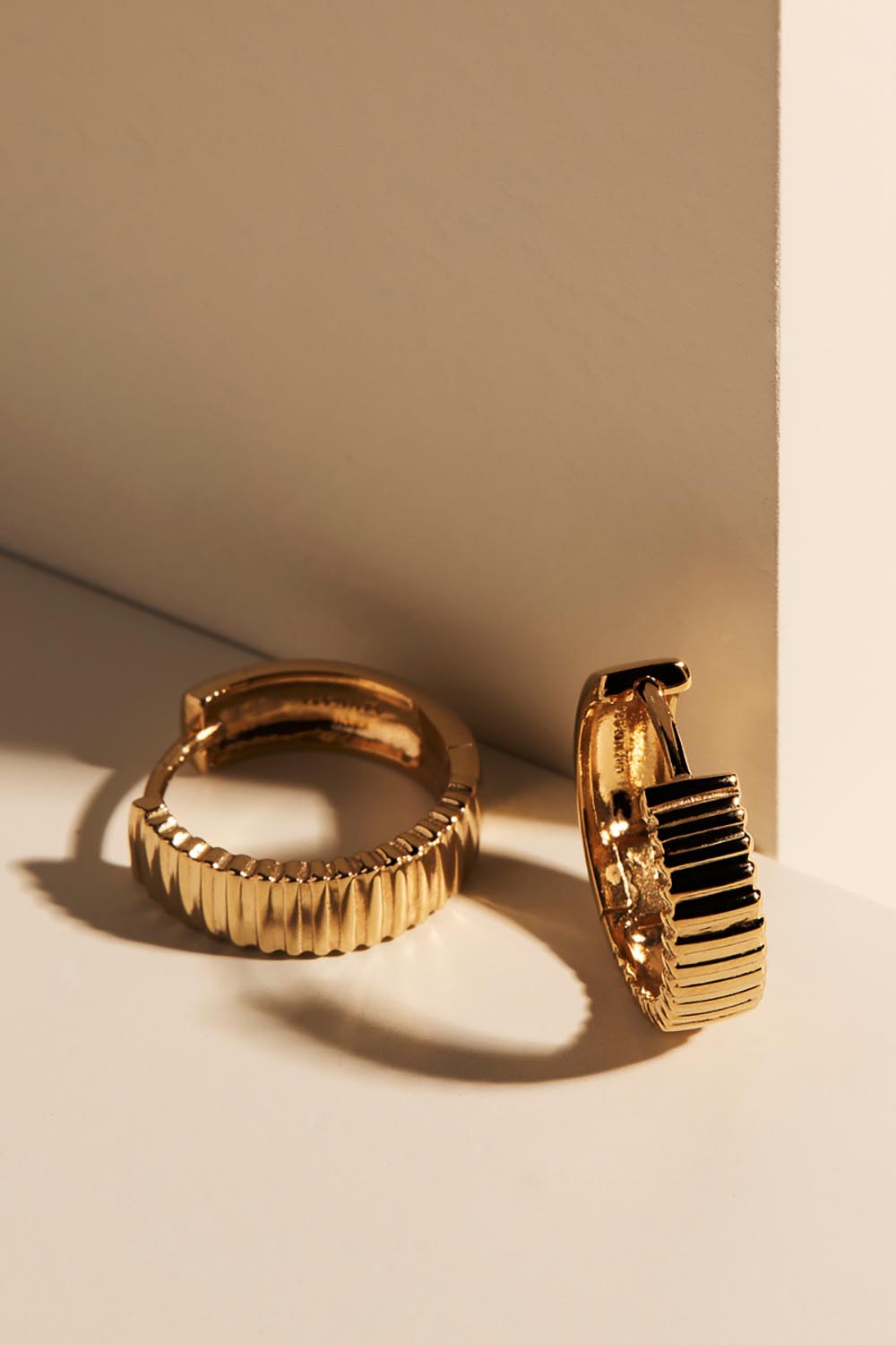 A model wearing the Raya Huggie Earring in colour Gold (Metallics), from the front, showing the whole outfit