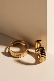 A model wearing the Raya Huggie Earring in colour Gold (Metallics), from the front, showing the whole outfit
