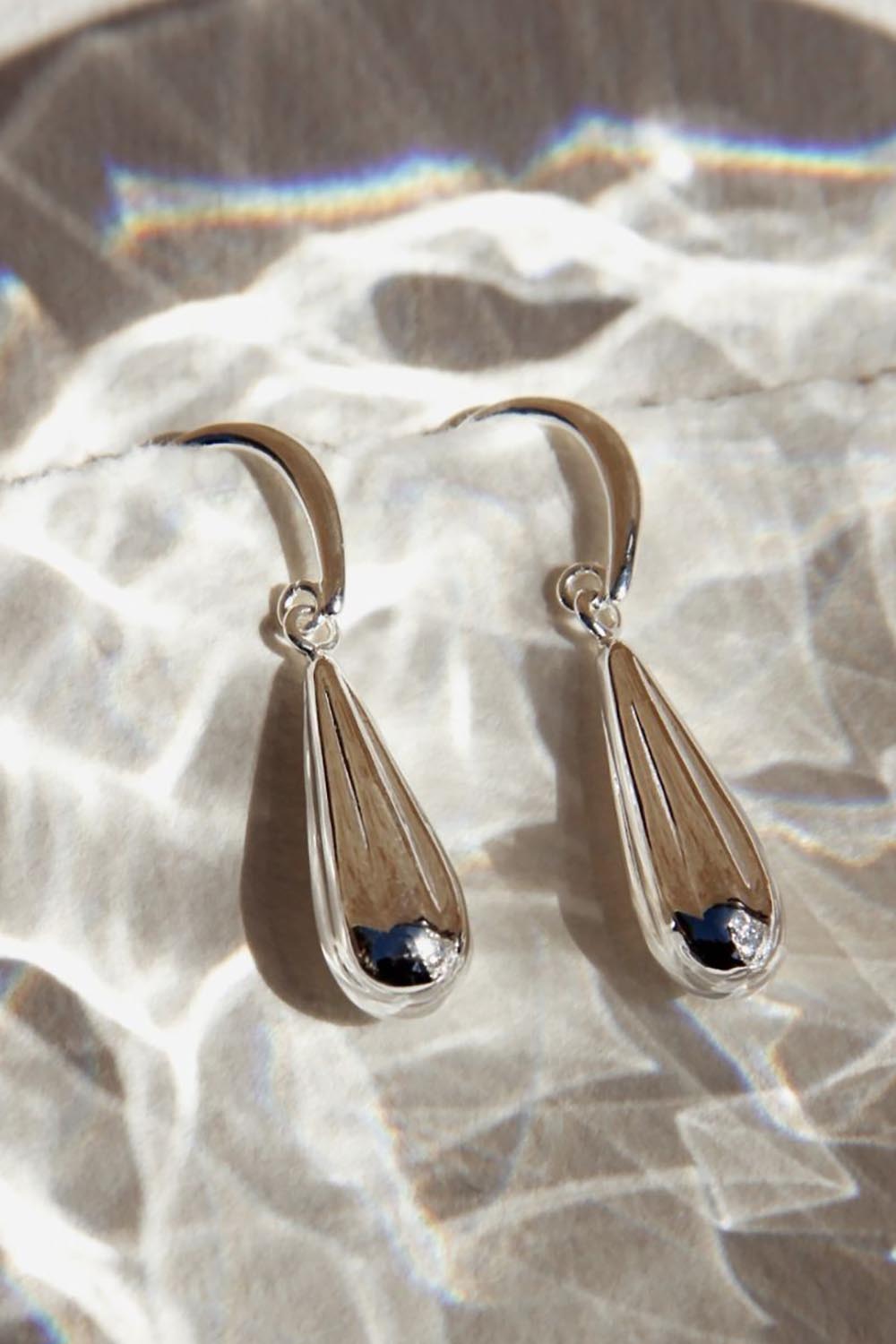A model wearing the Raya Baton Drop Earring in colour Silver (Metallics), from the front, showing the whole outfit