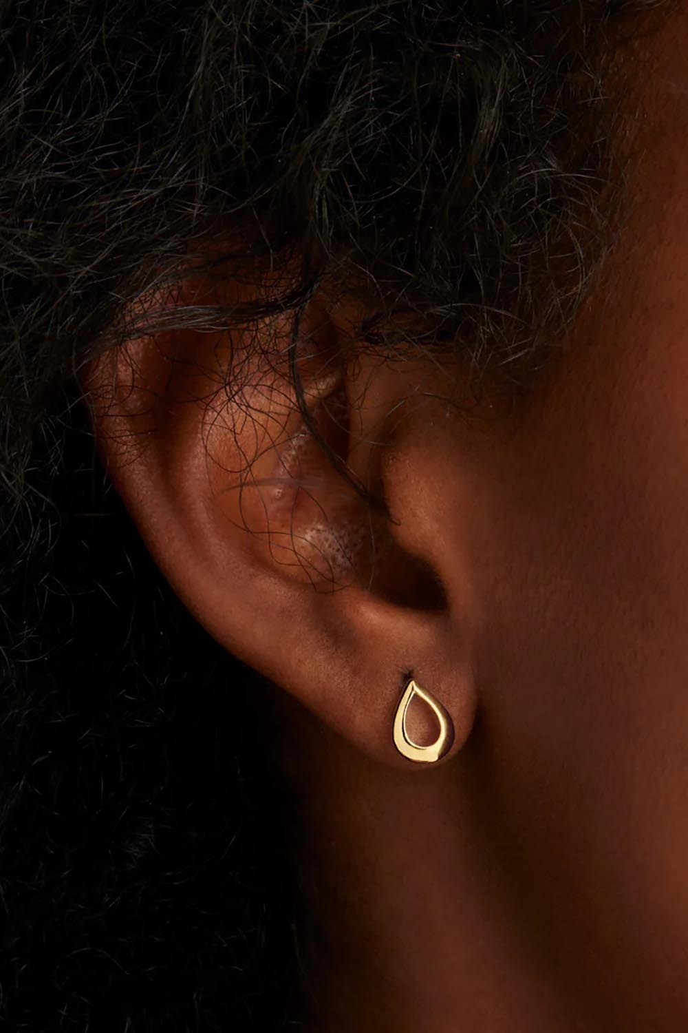 A model wearing the Chiara Yellow Gold Studs in colour Gold (Metallics), from the front, cropped image
