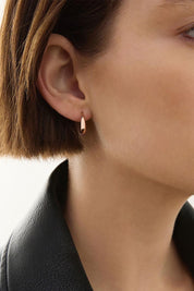 A model wearing the La Muse Rose Gold Stud Hoop Earring in colour Rosegold (Metallics), from the front, cropped image