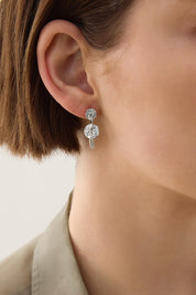 A model wearing the Milleluci Silver Circular Petite Drop Earring in colour Silver (Metallics), from the front, cropped image