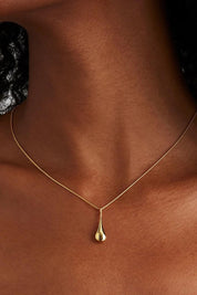 A model wearing the My Silent Tears Necklace in colour Gold (Metallics), from the front, cropped image