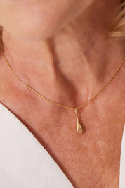A model wearing the My Silent Tears Necklace in colour Gold (Metallics), from the front, cropped image