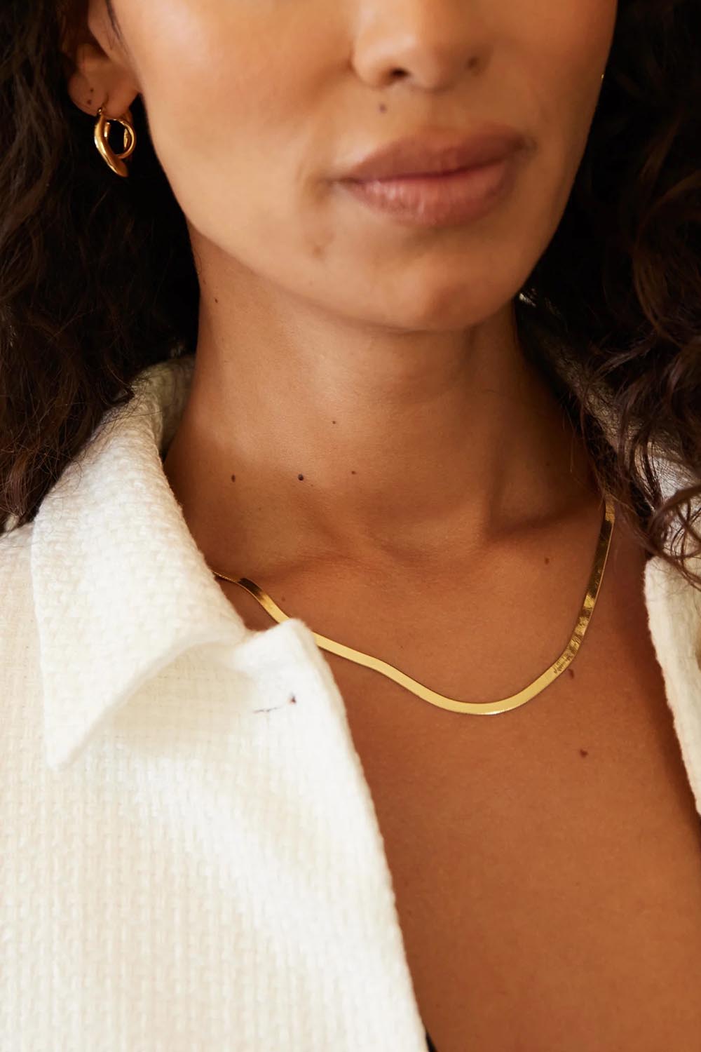 A model wearing the Herringbone Yellow Gold Necklace in colour Gold (Metallics), from the front, cropped image