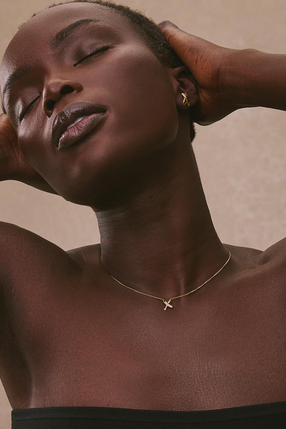 A model wearing the Bisous Yellow Gold Necklace in colour Gold (Metallics), from the front, cropped image