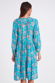 Model Madeline wearing size S of the Molly Dress in colour Derpink (Blue), from the back