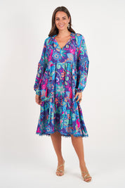 A model wearing the Molly Dress in colour Enigma (Blue), from the front, showing the whole outfit
