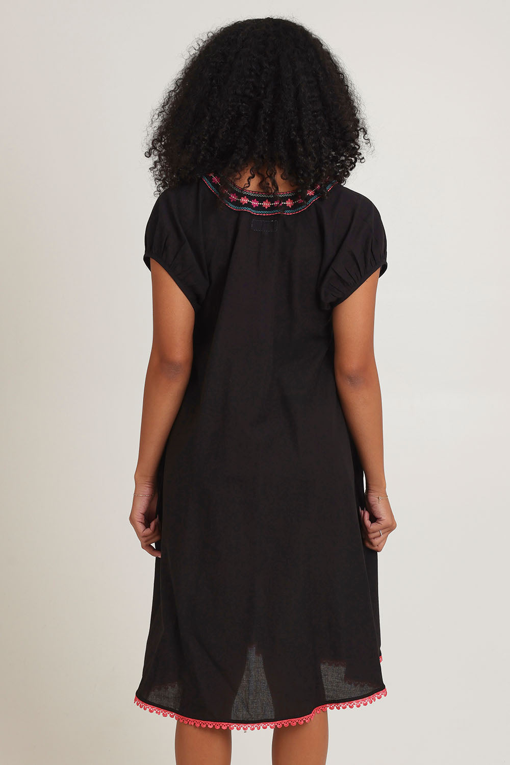 Model Ziara wearing size S of the Sao Paulo Cotton Dress in colour Rubyblk (Black), from the back