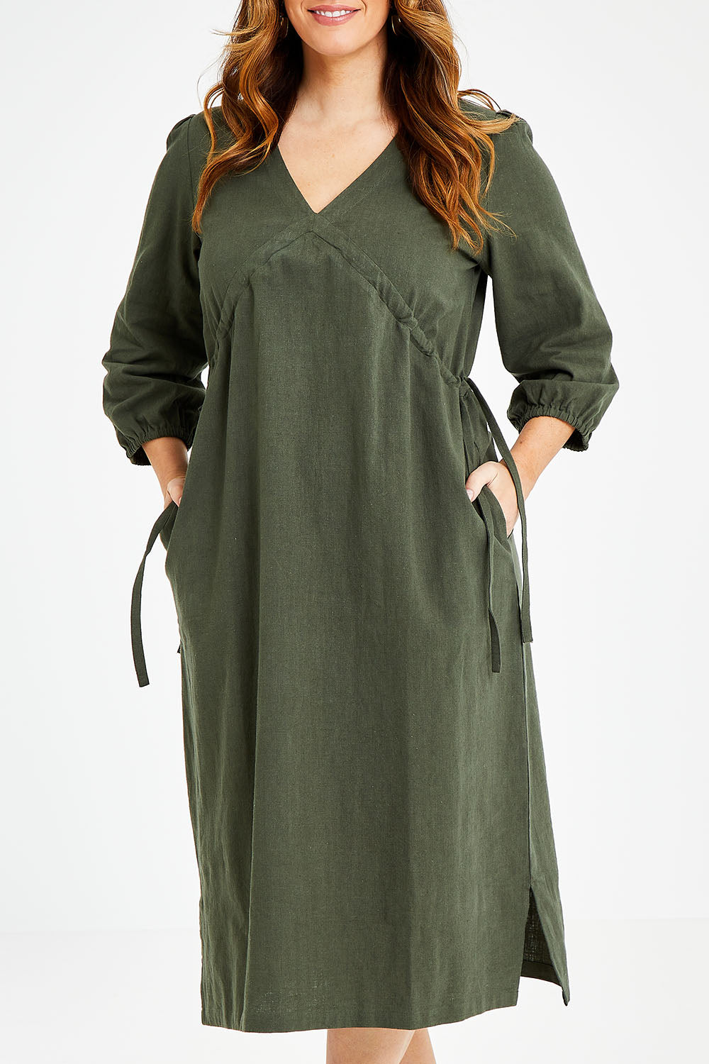 Model Laura wearing size 14 of the Ramie Empire Line Dress in colour Green (Green), from the front, cropped image