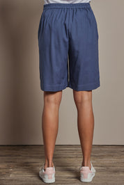 Model Amanda wearing size 10 of the Linen Cotton Pull On Shorts in colour Denim (Blue), from the back
