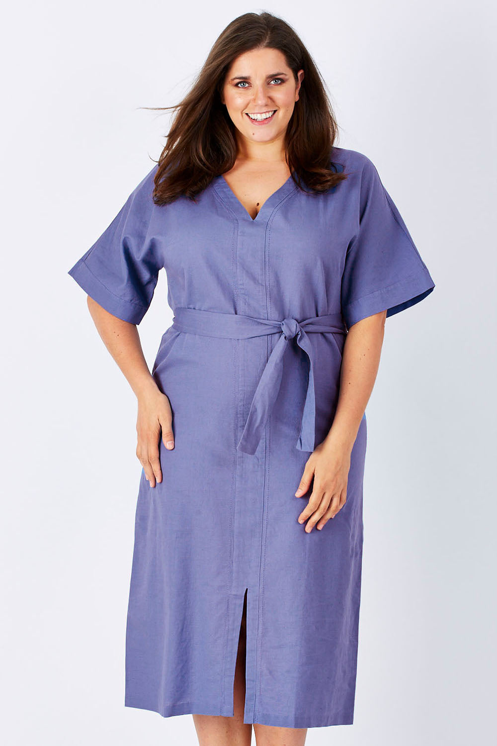 Model Mae wearing size 18 of the Natural Throw Dress in colour Fleet (Blue), from the front, cropped image