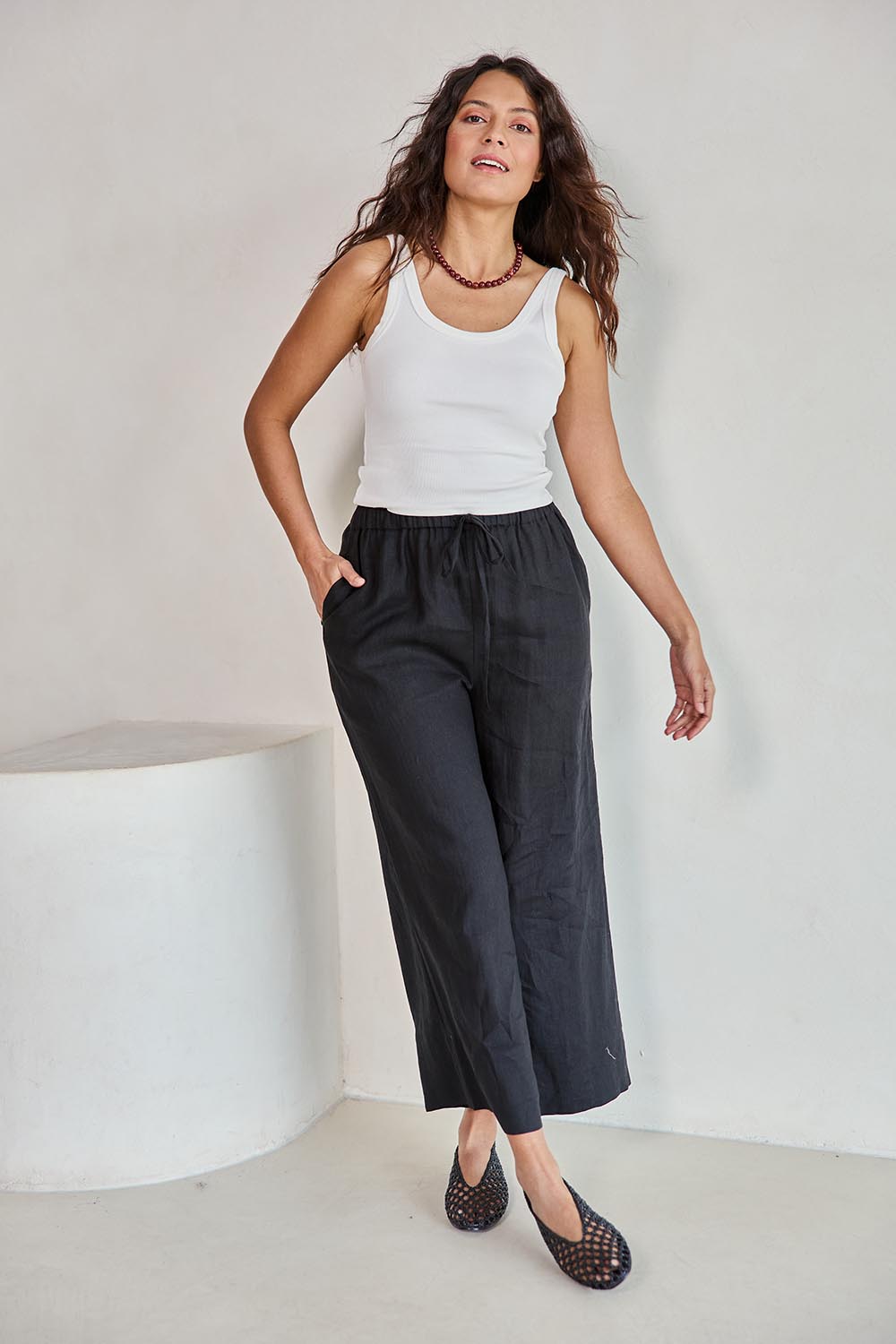 Model Tahneei wearing size 10 of the Linen Cropped Drawstring Pant – Black in colour Black, from the front